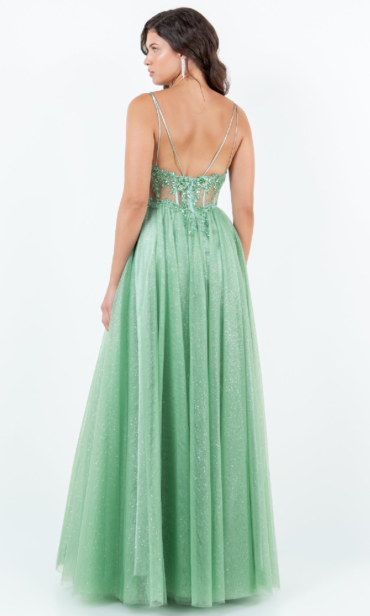 A woman models the Cinderella Couture 8238J Long Glitter Prom Dress, a sparkly light green A-line gown with thin straps and an open back, set against a plain white background.